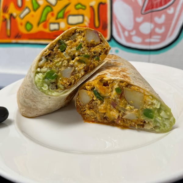 Two halves of a large, savory breakfast burrito filled with eggs, potatoes, and green peppers.